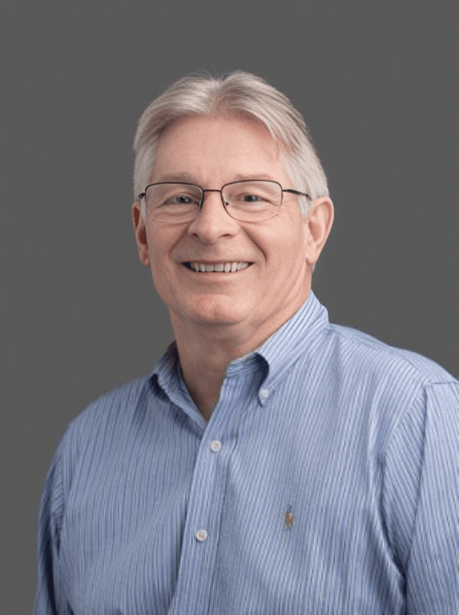 Smiling man in glasses and blue shirt.