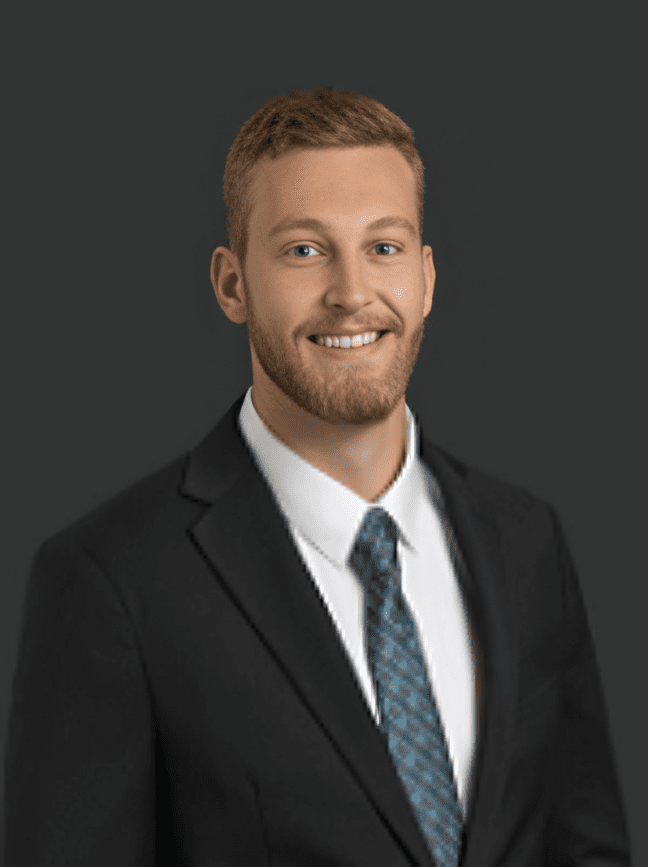 Smiling man in suit with dark background.