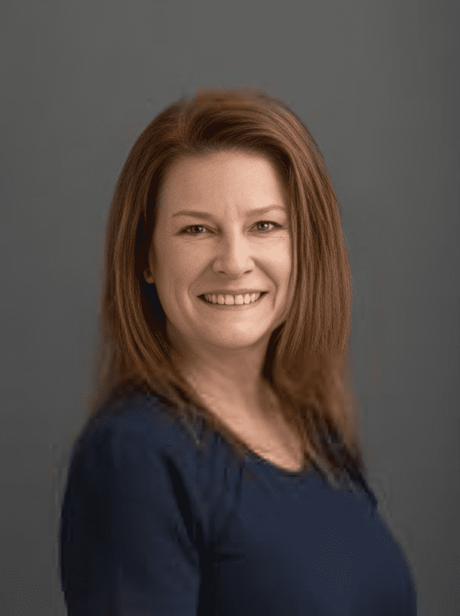 Woman smiling in front of gray background.