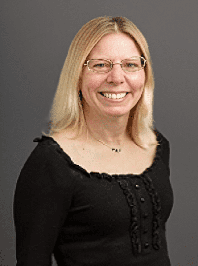 Smiling woman with glasses and blonde hair.
