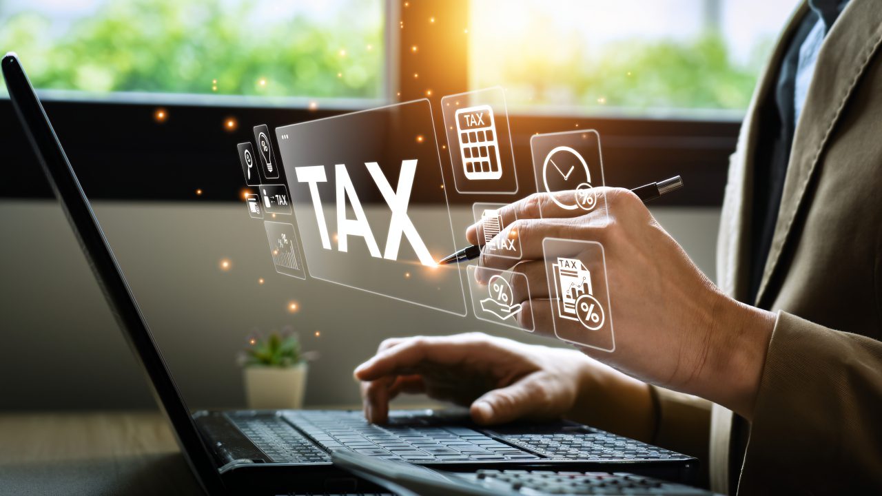Person using laptop with tax icons displayed.