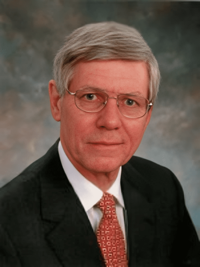 Elderly man in suit with glasses.